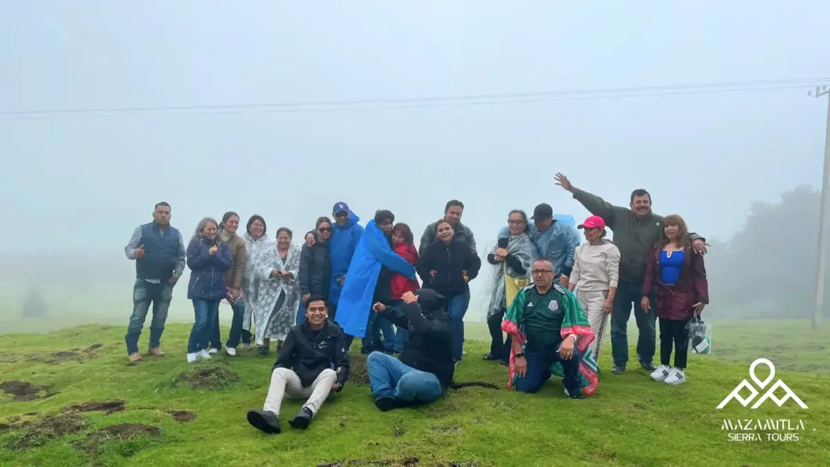 Grupo de visitantes en un prado con niebla